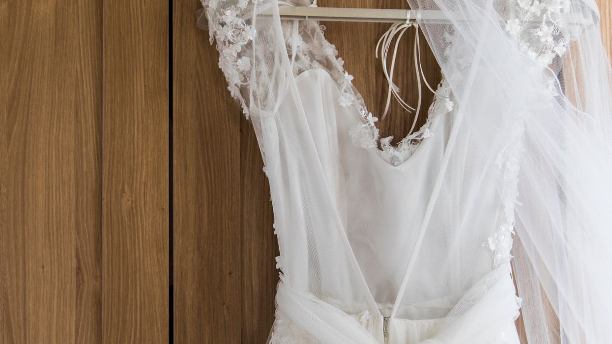 <p>Wedding dress hanging against a wooden background</p>