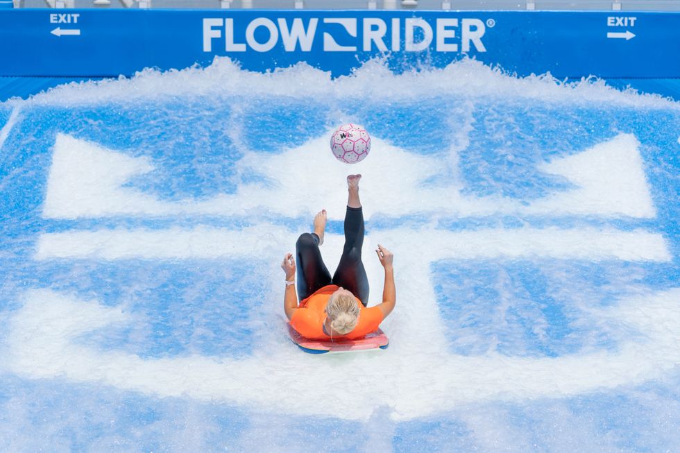 Woman lying down and kicking a football in the air