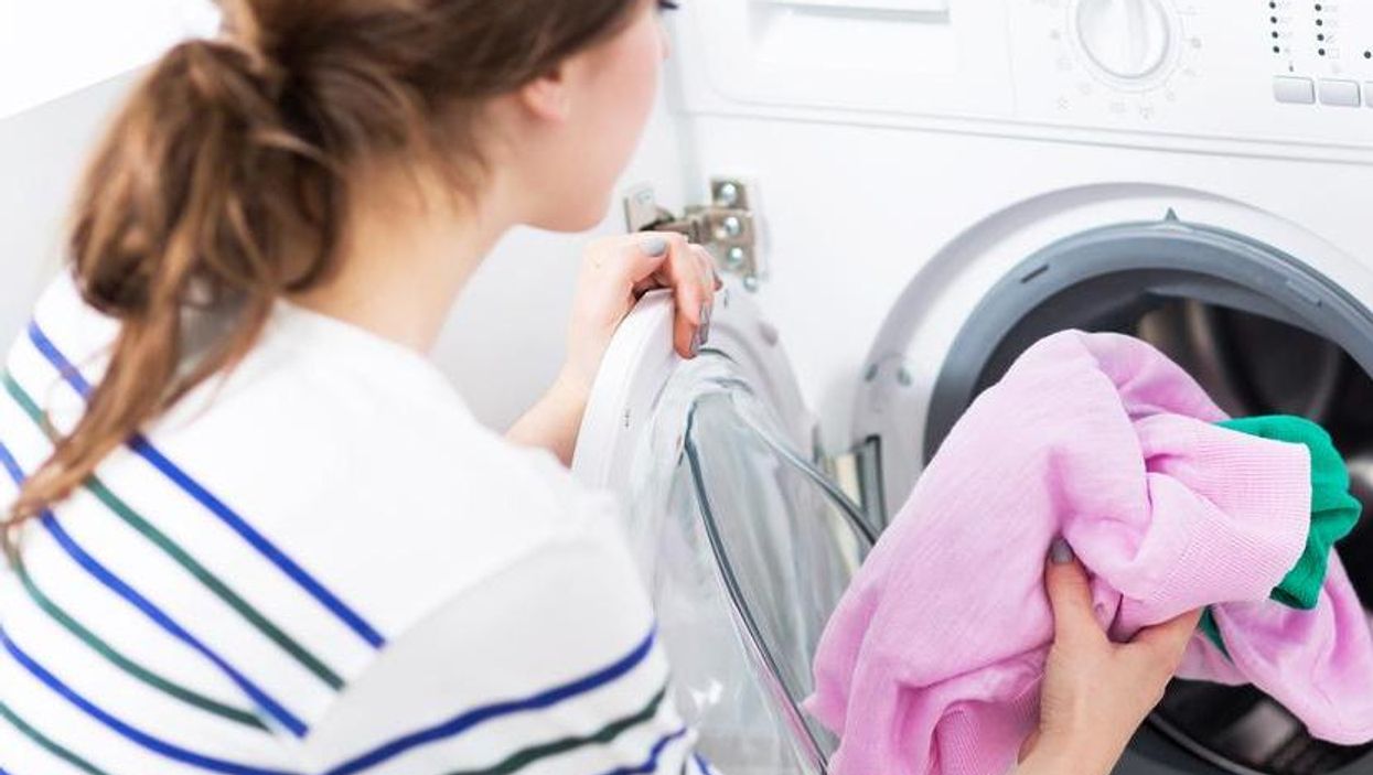 Woman Putting her Laundry into a Washing Machine.