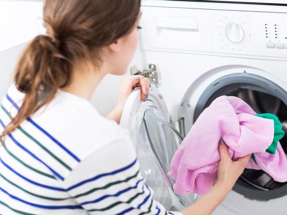 Woman Putting her Laundry into a Washing Machine