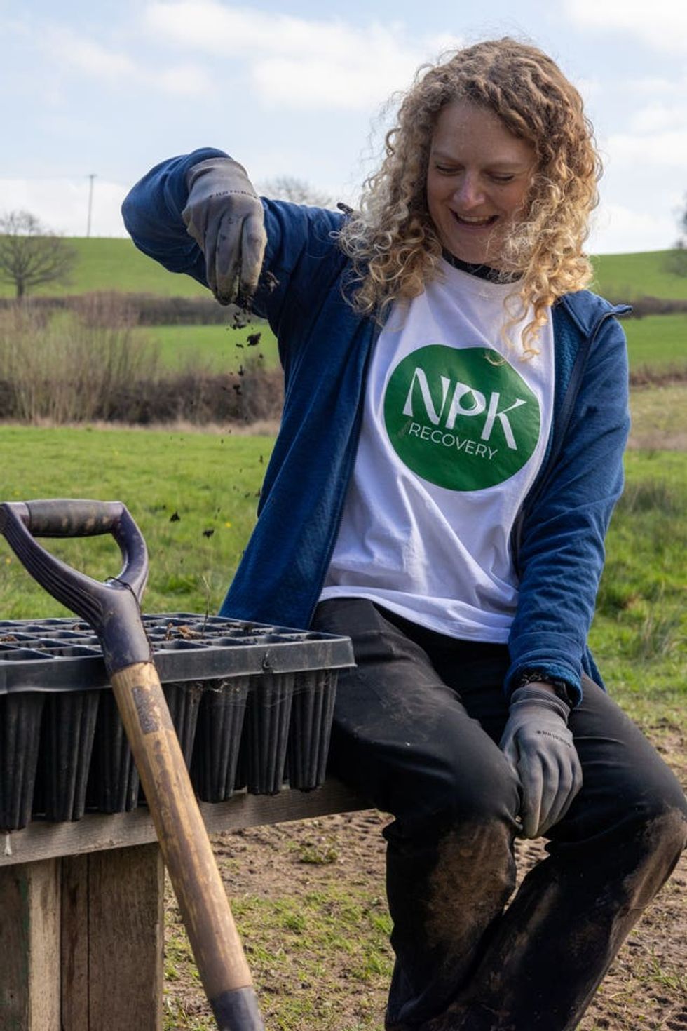Woman runs fertiliser through her gloved fingers