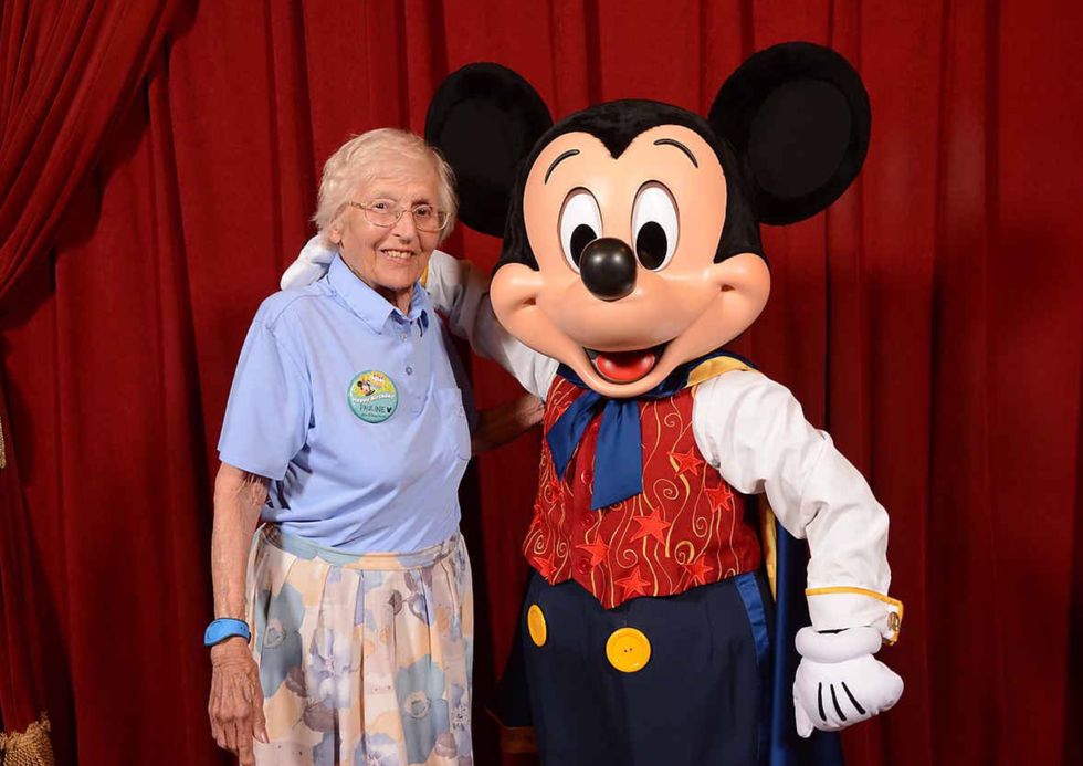 Woman standing next to Mickey Mouse and smiling