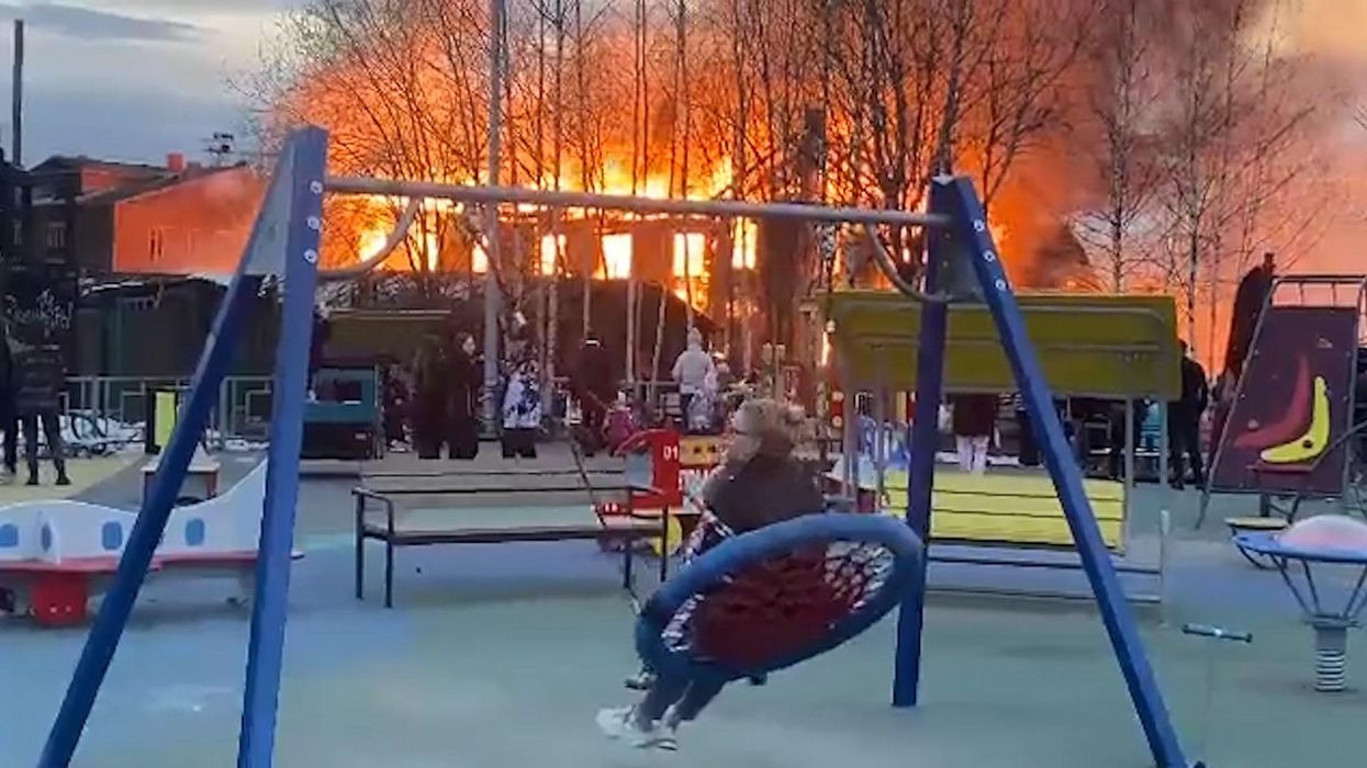 'This is fine': Woman swings in Russian playground as building burns nearby