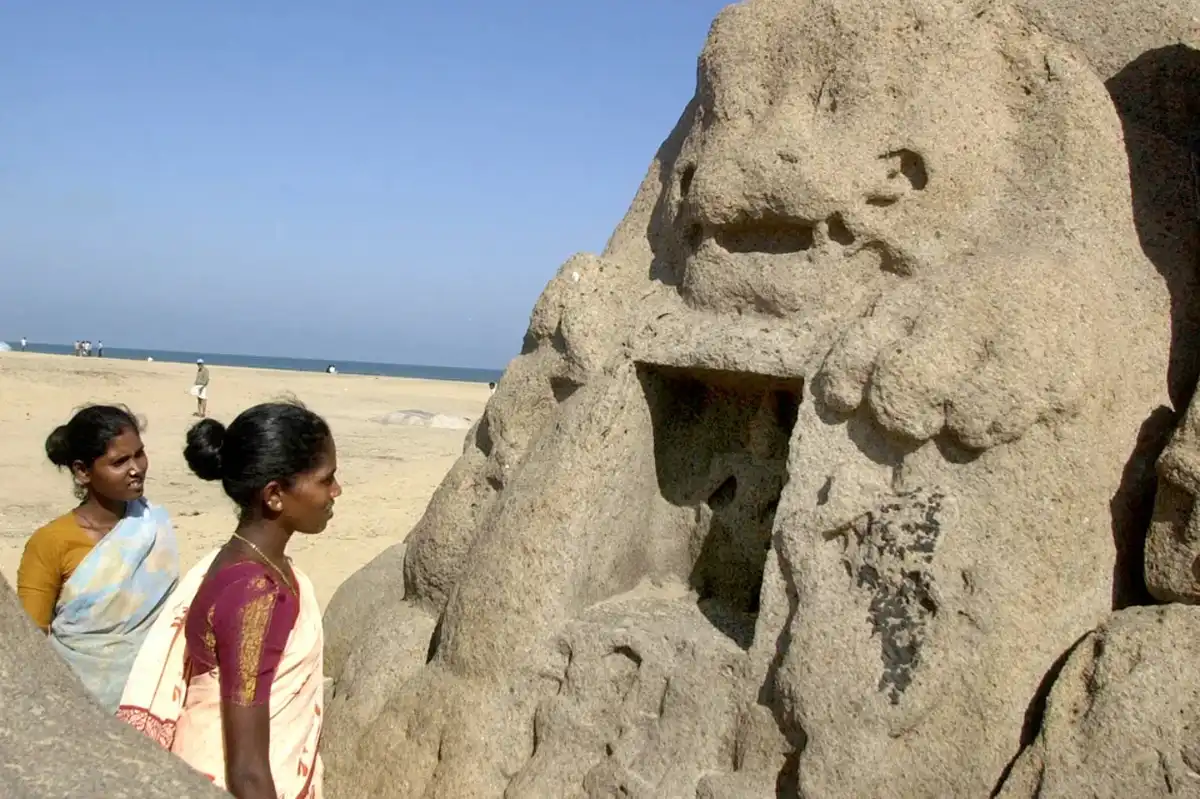 Women examine a lion head monument which was uncovered by the 2004 tsunami in Mahabalipuram, India