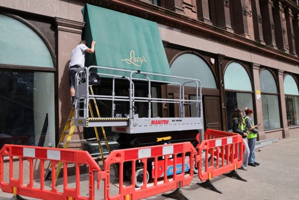 Workers place awnings above a shop window
