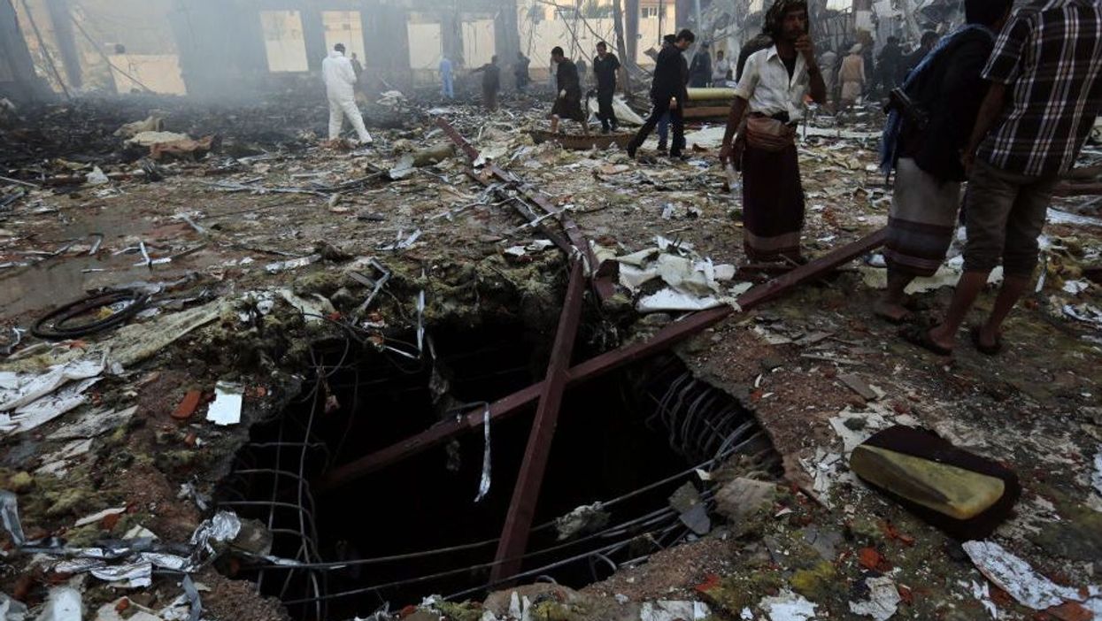 Yemenis inspect the site of Saudi-led airstrikes that hit a funeral ceremony in Sanaía