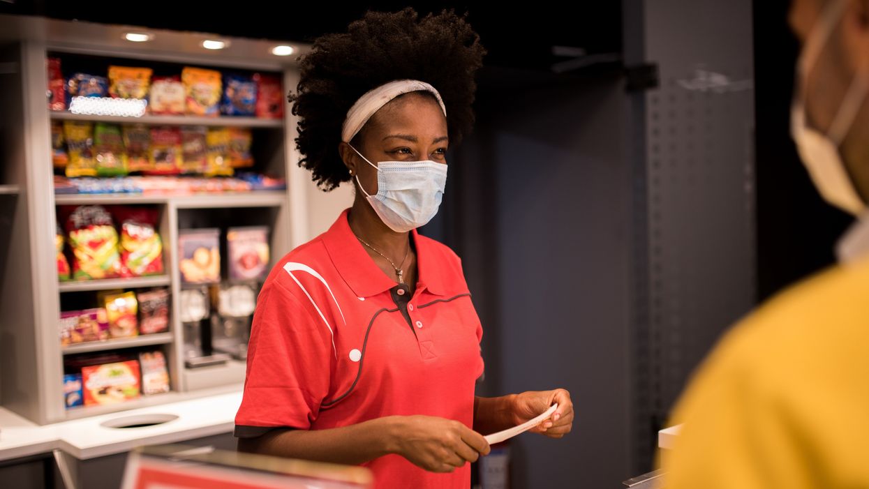 Young African-American woman working at the bar in the cinema, selling tickets, fast food and refreshment.