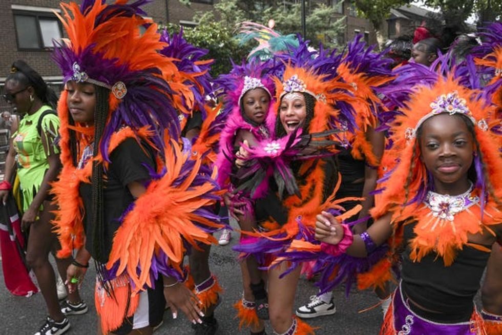 Young paradegoers in orange and purple plumes